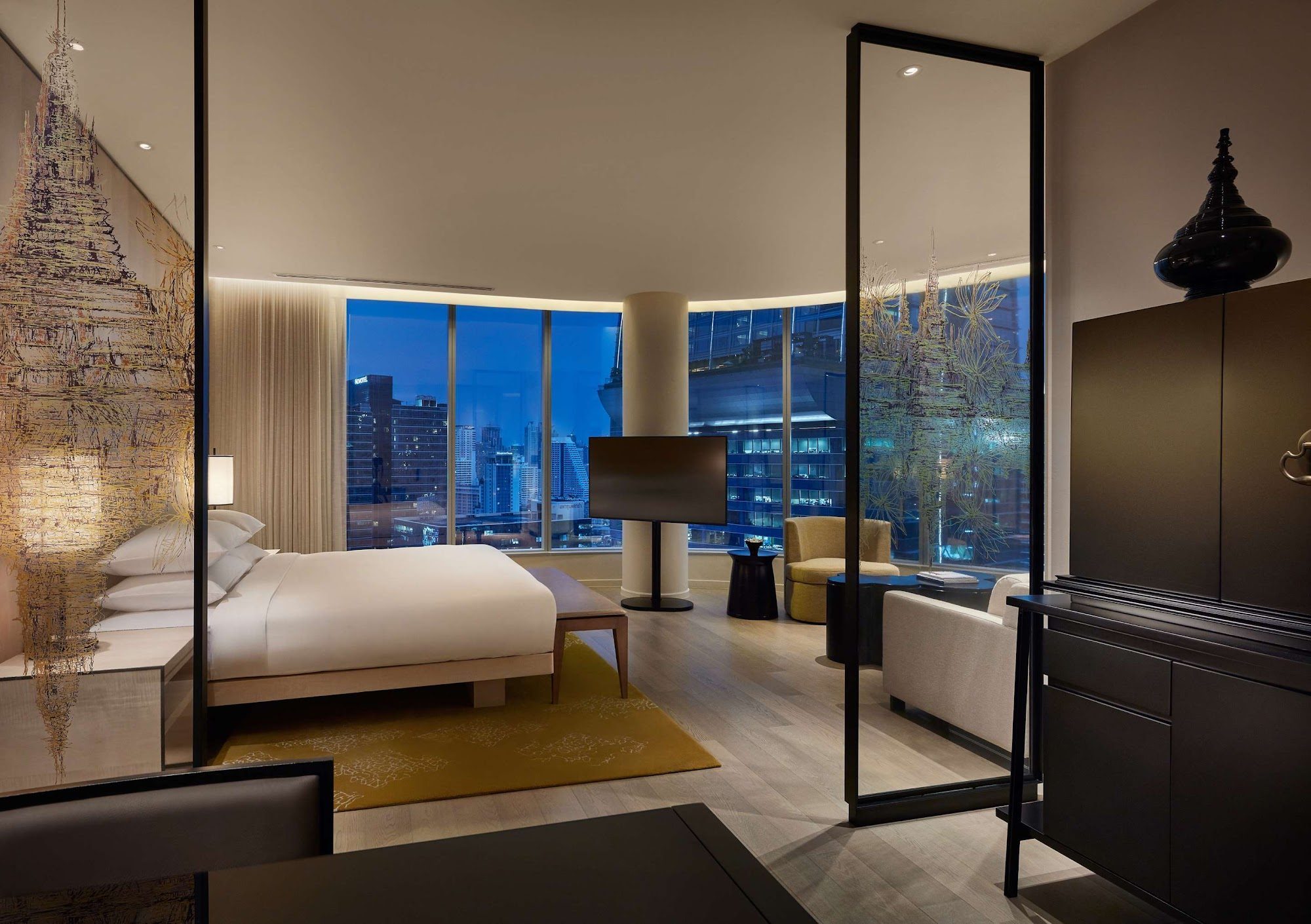 A corner king room at Park Hyatt Bangkok at dusk, floor to ceiling windows wrapping the Bangkok skyline beyond the bed.