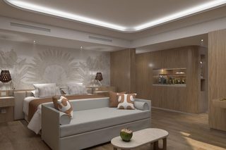A modern hotel room with a sofa, a small table, and a minibar.