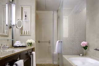 A modern bathroom with a glass shower enclosure, a bathtub, and a vanity with a mirror and toiletries.