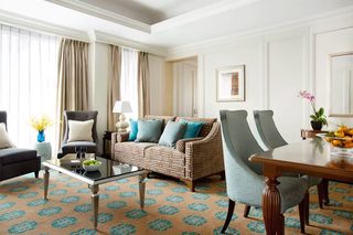 A well-lit living room with a sofa, armchairs, a coffee table, and a dining table.