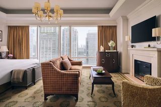 A hotel room with a large bed, a sofa, a coffee table, a fireplace, and a TV.