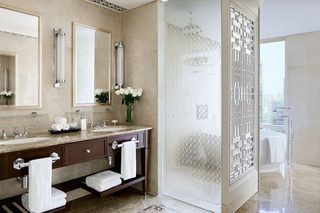 A modern bathroom with a large mirror, two sinks, a vanity, and a glass shower enclosure.