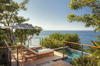 A poolside area with lounge chairs and a view of the ocean.