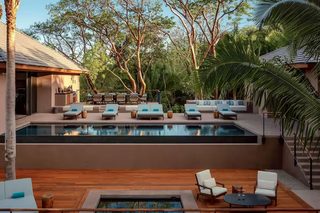 A modern outdoor pool area with lounge chairs and a wooden deck.
