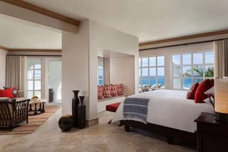A hotel room with a large bed, a seating area with a view, and a dining table.