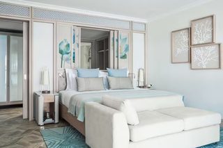 A modern bedroom with a bed, nightstands, a sofa, and artwork on the walls.