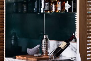 A bar area with shelves of liquor bottles, a bottle of whiskey, a bottle of gin, and a bottle of vodka.