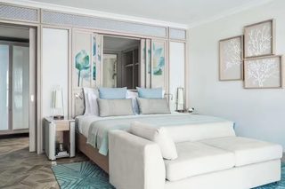 A bedroom with a bed, bedside tables, a sofa, a wardrobe, and artwork on the walls.