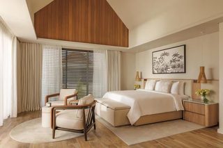 A modern bedroom with a large bed, a wooden ceiling, and a painting on the wall.