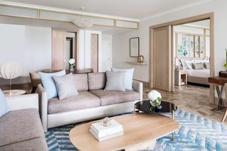 A modern living room with a sofa, coffee table, and a dining area.