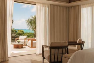 A hotel room with a balcony, a bed, a chair, and a table.