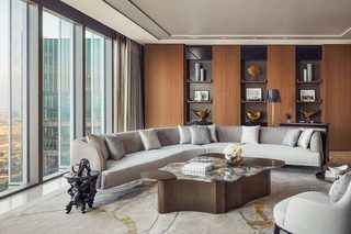 A modern living room with a large sectional sofa, a coffee table, and a bookshelf.