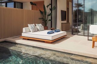 A modern outdoor living area with a built-in sofa, a potted plant, and a clear swimming pool.