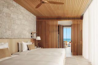 A modern hotel room with a large bed, wooden ceiling, and a view of the sea.