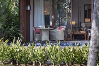 A well-lit room with a large window, a dining table with chairs, and a view of the outdoors.