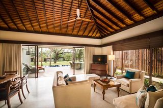 A spacious living area with a wooden ceiling, a sofa, a television, and a dining table.