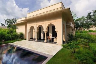 A traditional building with a pool, surrounded by greenery.