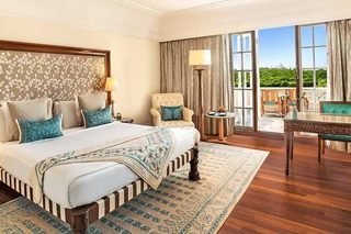 A spacious hotel room with a large bed, a sitting area with a view, and a balcony.