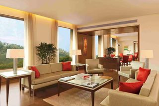 A spacious living room with a sofa, armchairs, a coffee table, and a dining area in the background.