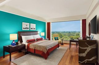A hotel room with a large bed, a desk, a chair, and a TV.