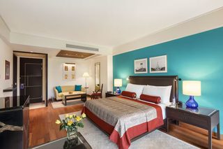 A hotel room with a large bed, a sofa, a desk, and a nightstand.