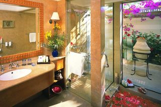 A bathroom with a large sink, mirror, and shower area.