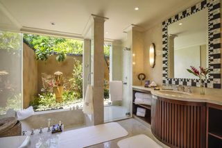 A modern bathroom with a glass shower, a large mirror, and a view of a garden.