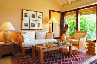 A well-lit room with a sofa, two chairs, a coffee table, and a wall-mounted picture frame.