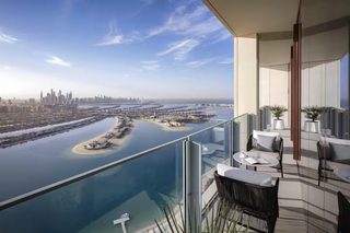 A high-rise balcony with a clear view of a coastal cityscape, including a marina and a large body of water.