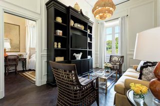 A living room with a dark wooden bookshelf, a beige sofa, and a wicker chair.