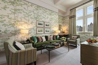A living room with a green sofa set, a coffee table, and a view of a cityscape through a window.