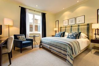 A hotel room with a bed, a desk, a chair, a small table, and a window.