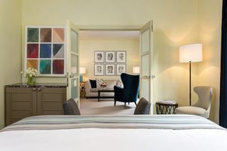 A hotel room with a bed, a desk, a chair, a sofa, and a lamp.