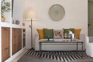 A living room with a sofa, a coffee table, a lamp, and a decorative plate on the wall.