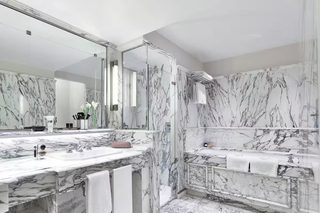 A modern bathroom with marble countertops, a large mirror, and a walk-in shower.