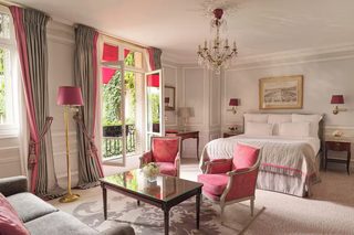 A hotel room with a bed, a chair, a table, and a chandelier.