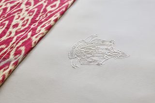 A fabric with a pink and white pattern and a white embossed design.