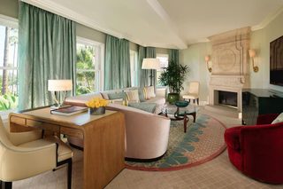 A modern living room with a curved sofa, a red chair, a glass coffee table, and a fireplace.