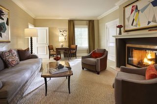 A living room with a sofa, armchairs, a coffee table, a fireplace, and a dining area with a table and chairs.