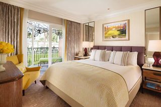 A hotel room with a large bed, a chair, a nightstand, and a view of the outdoors.
