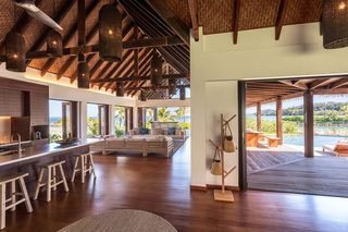 A spacious kitchen with a large island, wooden bar stools, and a view of the ocean.