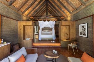 A room with a bed, a sofa, a small table, and a ceiling fan.