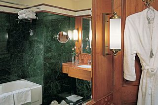 A bathroom with a marble sink, a large mirror, and a robe hanging on the wall.
