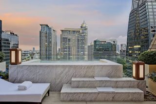 A rooftop terrace with a bed and seating area, offering a city skyline view.
