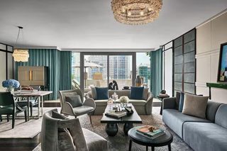 A modern living room with a sofa, chairs, a coffee table, and a chandelier.