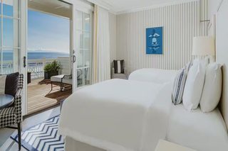 A hotel room with a large bed, a seating area with a view of the ocean, and a painting on the wall.