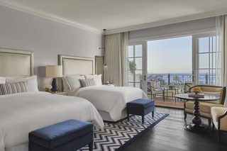 A hotel room with two beds, a balcony with a view, and a dining area.