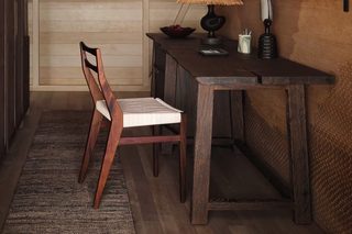 A wooden interior with a desk, chair, and a framed picture of the ocean.