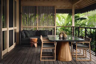 A wooden deck with a table and chairs, a sofa, and a decorative wooden stool.